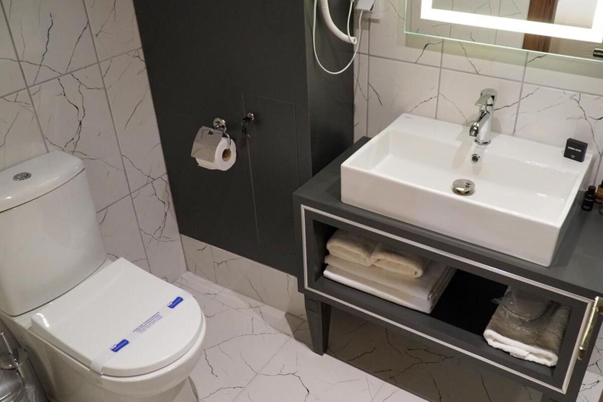 A bathroom with a toilet, a sink, a mirror, and a towel rack.