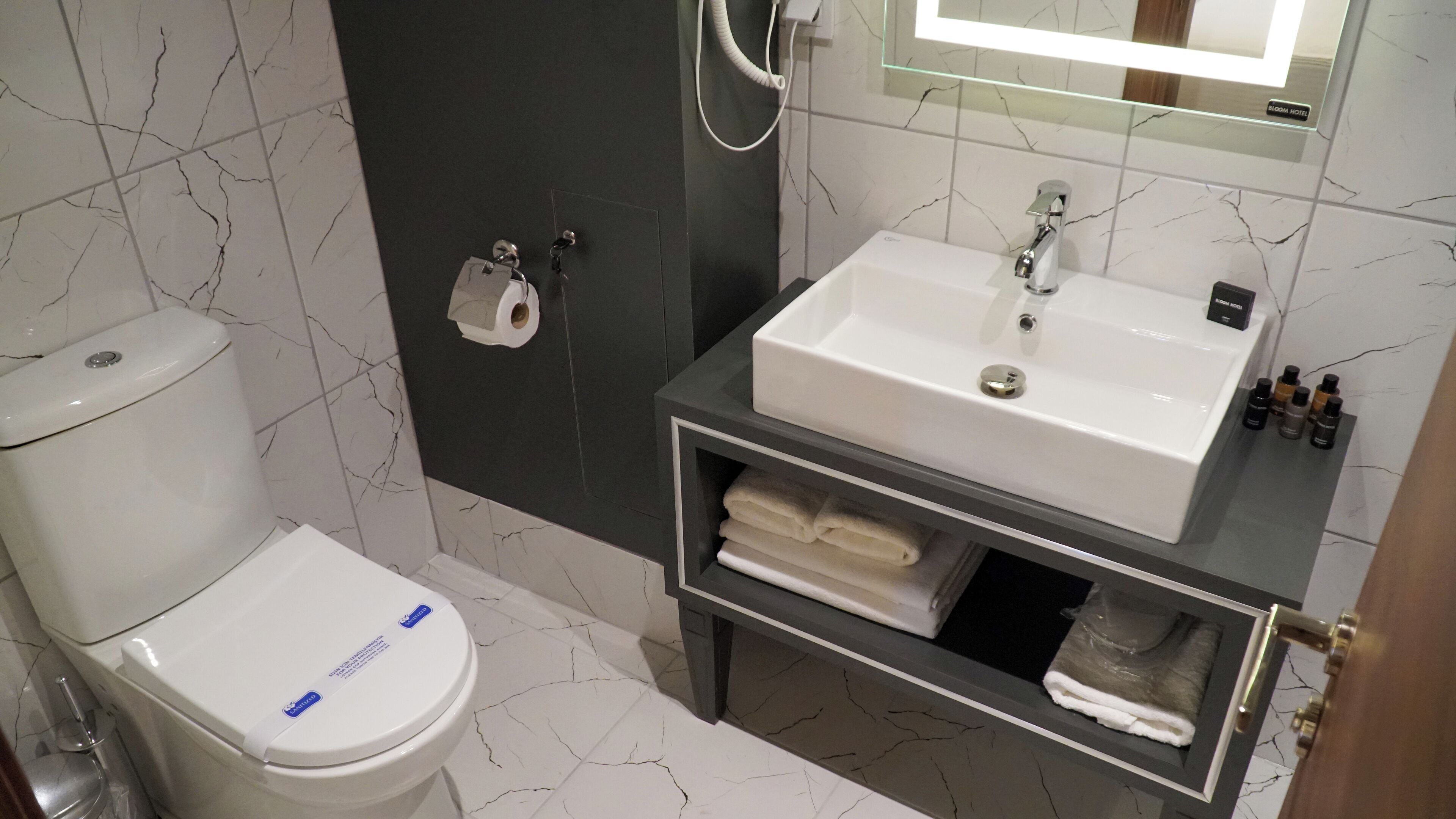 Un baño con inodoro, lavamanos y toallero.