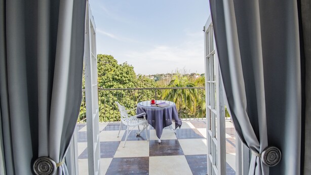 Un balcon avec un sol à carreaux, une table recouverte d’une nappe et une chaise.