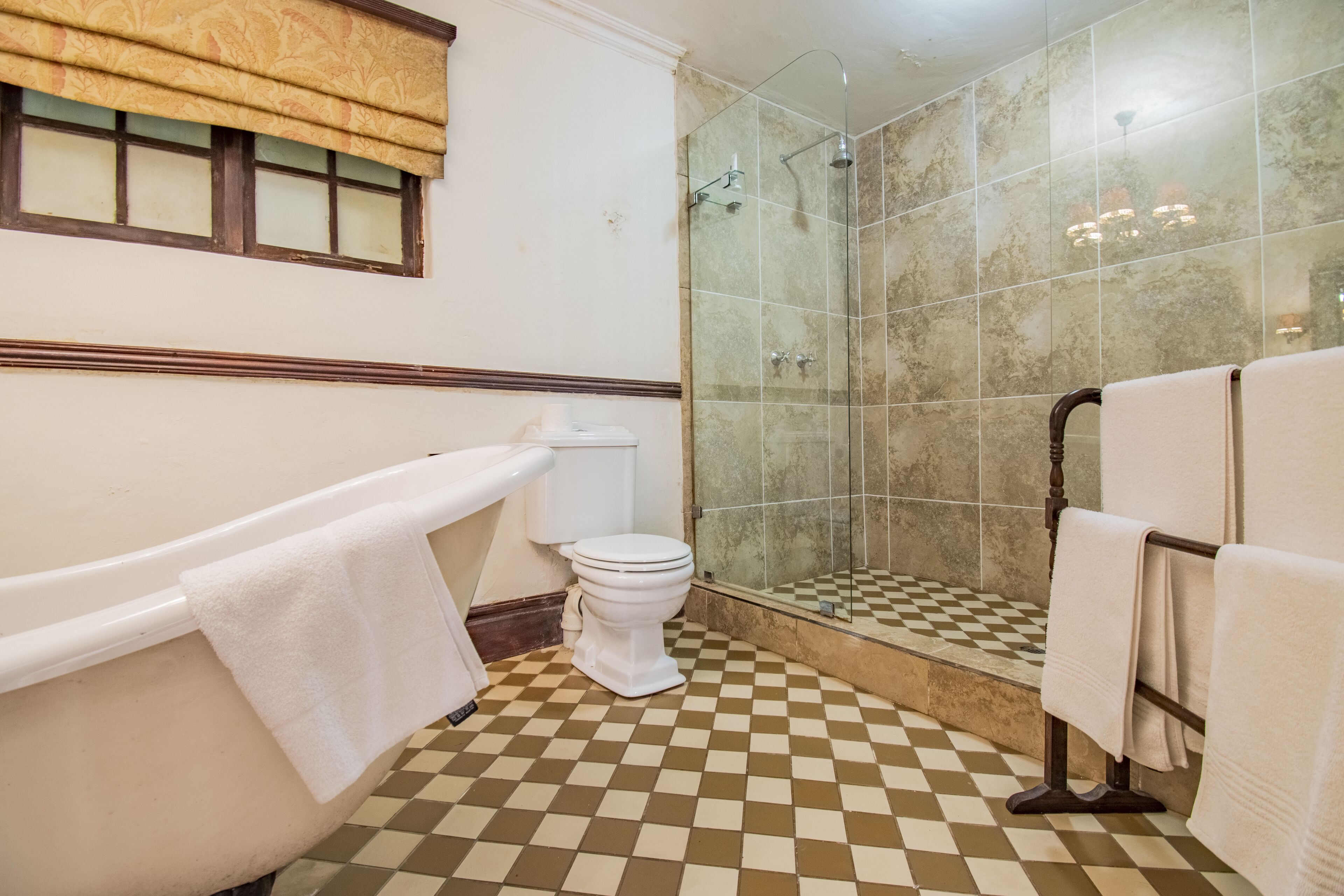 Une salle de bain avec un carrelage à motifs géométriques, une baignoire, des toilettes et une cabine de douche en verre.