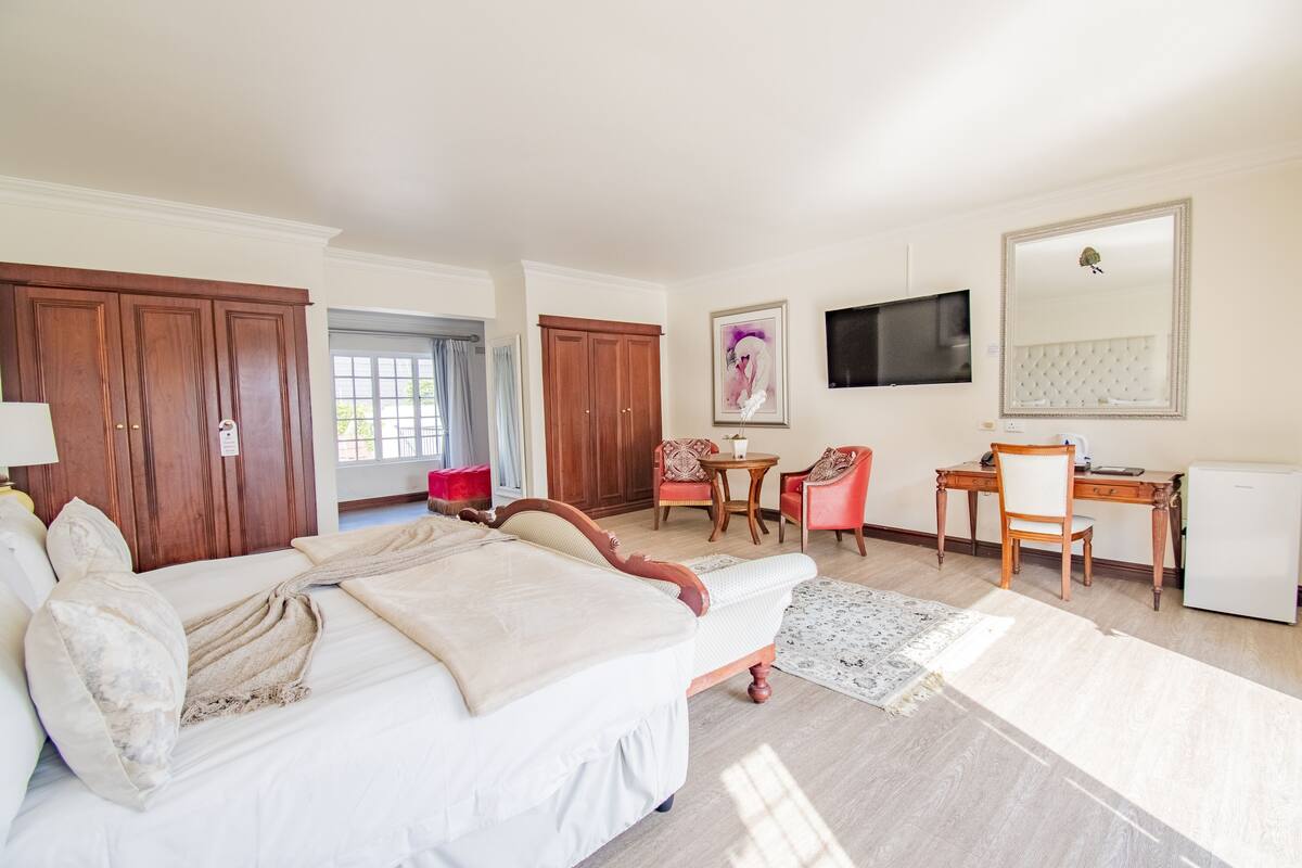 Una habitación de hotel con una cama grande, un escritorio, una silla, un televisor y un armario.