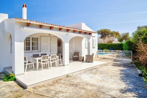 Ein weißes Gebäude mit einem Ziegeldach, Sitzgelegenheiten im Freien und einem Pool.