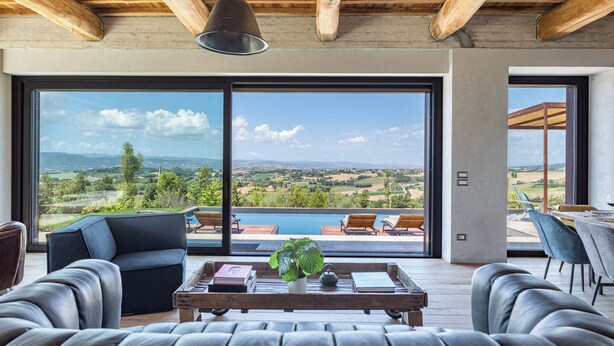 A spacious living area with a large sliding glass door leading to a pool and scenic outdoor views. - Casale The Place 6+2, Emma Villas (San Damiano)