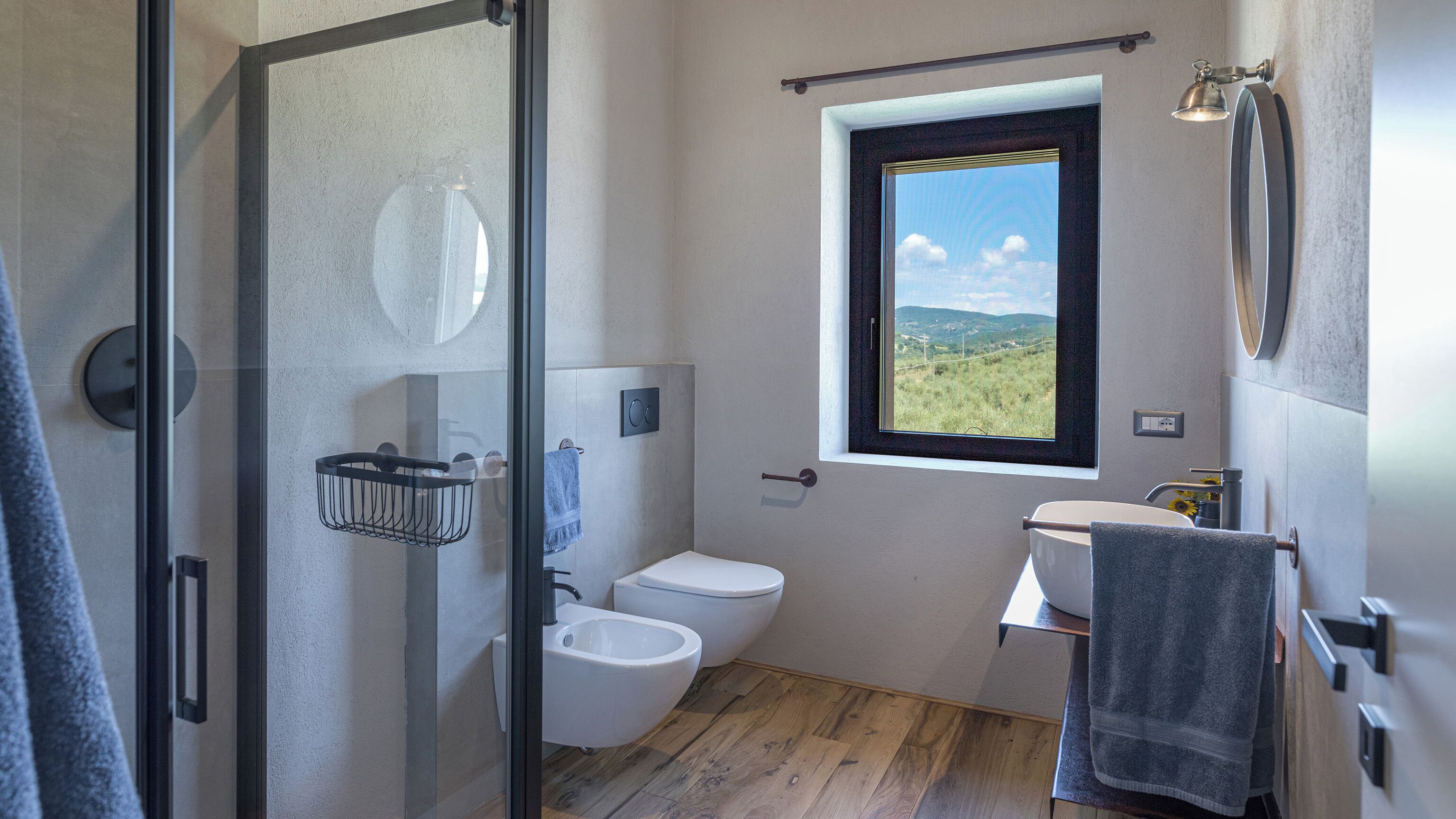 Une salle de bain moderne dotée d’une douche à parois de verre, de toilettes, d’un bidet et d’un lavabo avec un porte-serviettes.