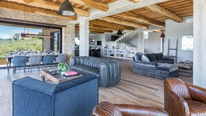 A spacious living area with a wooden ceiling, leather sofas, and a dining area with chairs and a table. - Casale The Place 6+2, Emma Villas (San Damiano)