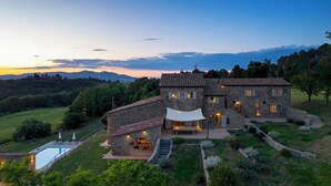 Una casa de piedra con piscina, mobiliario exterior y vistas al campo circundante.