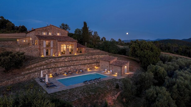 Un edificio de piedra grande con piscina y mobiliario exterior.