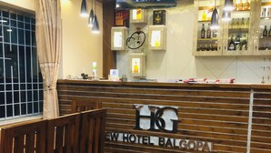 Un comptoir d’accueil avec un revêtement en bois et une enseigne indiquant : « NOUVEL HÔTEL BALGOPAL ».