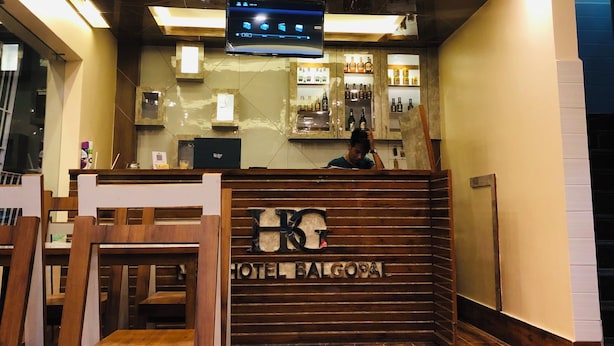 Un hall d’accueil d’hôtel avec un comptoir en bois, un téléviseur fixé au mur et un bar avec des étagères remplies de bouteilles.