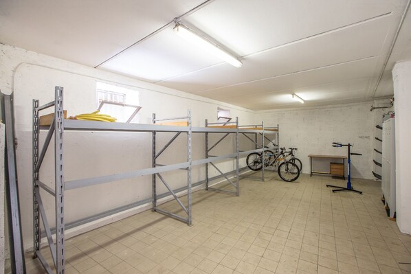 Una habitación limpia y bien iluminada con estanterías de metal, una bicicleta y un escritorio con una silla.