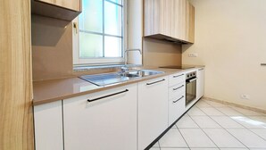 A modern kitchen with a window, stainless steel sink, and white cabinets. - Casa Alpina - Aosta (Aosta)