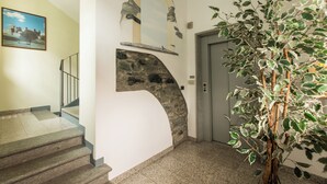A staircase with a stone arch, a wall-mounted mirror, and a potted plant. - Casa Alpina - Aosta (Aosta)