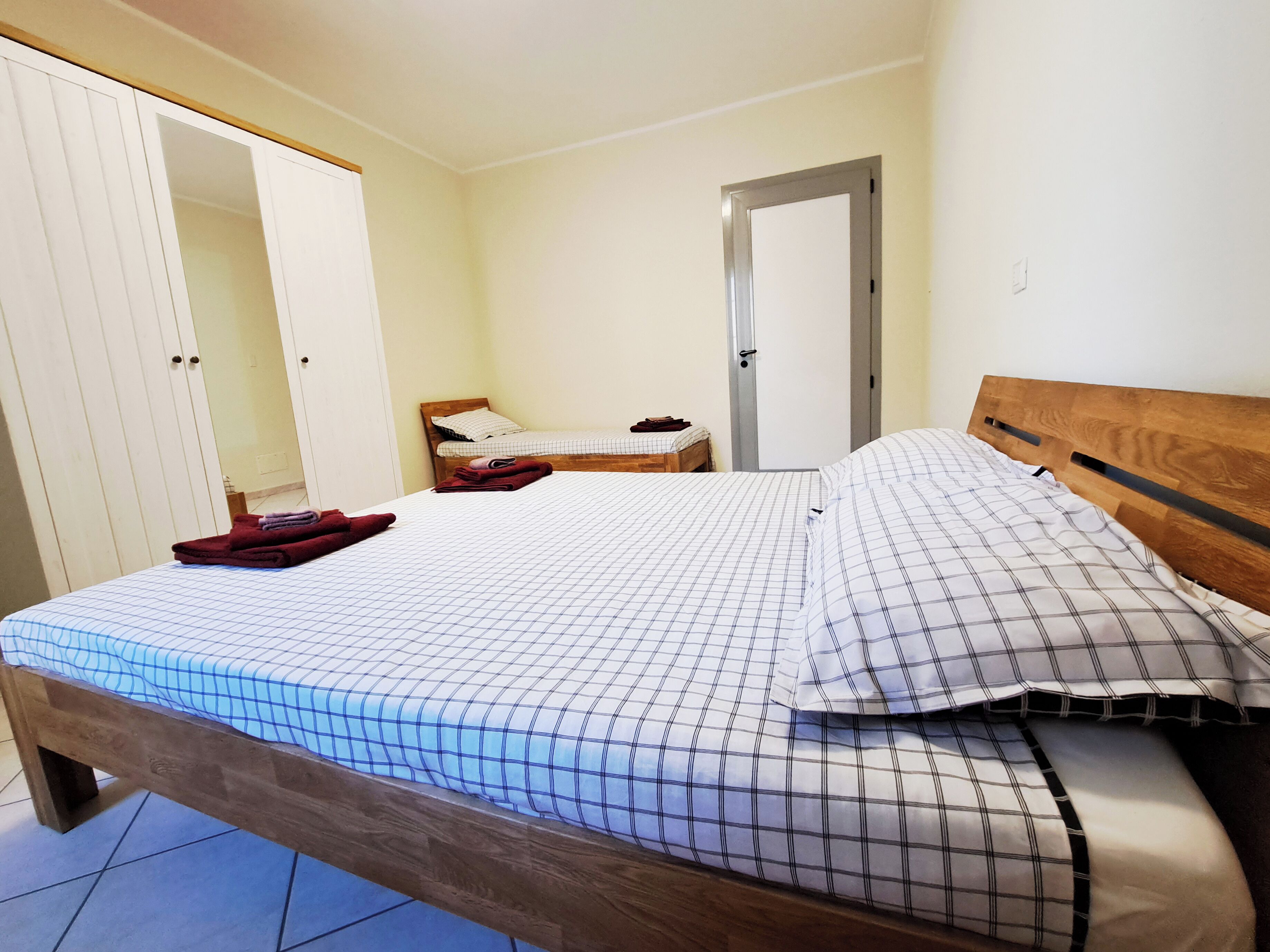 A bedroom with a wooden bed, a wardrobe, and a door.