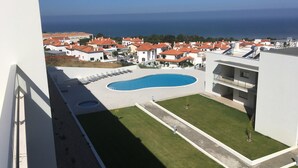 Zona de piscina amb vistes al mar, envoltada d'edificis amb teulades vermelles.