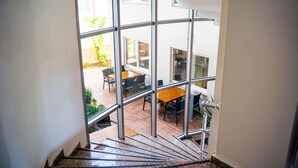 A staircase leading to a glass-enclosed area with a wooden table and chairs, and a view of the outside. - Şirin Rezidence (Denizli)