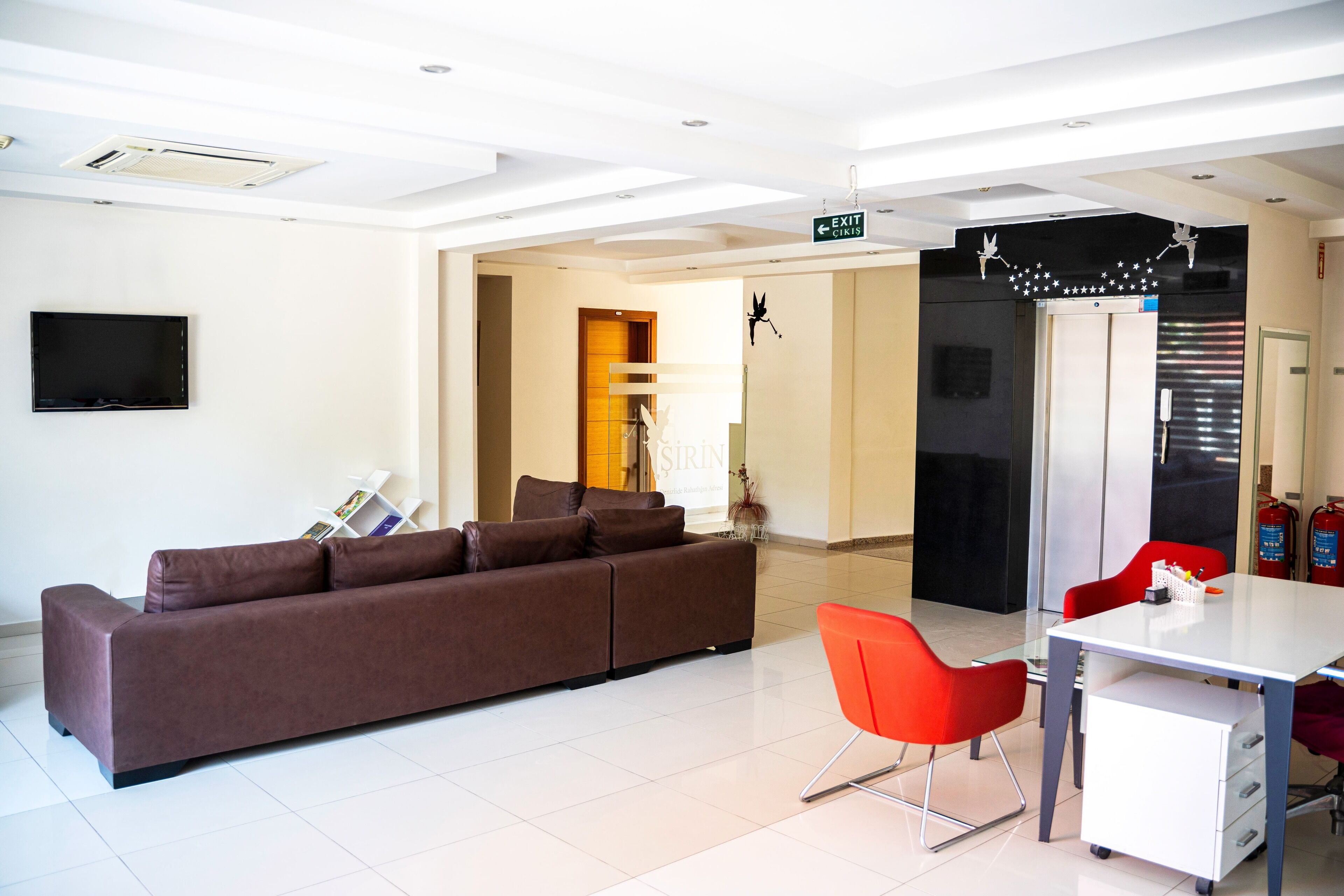 Una habitación de hotel moderna con sofá, una mesa de comedor y sillas rojas.