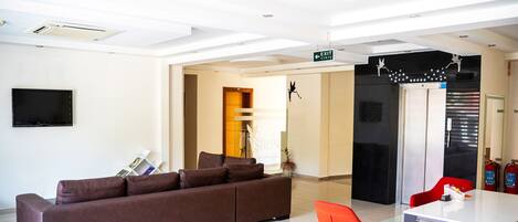 Una habitación de hotel moderna con sofá, una mesa de comedor y sillas rojas.