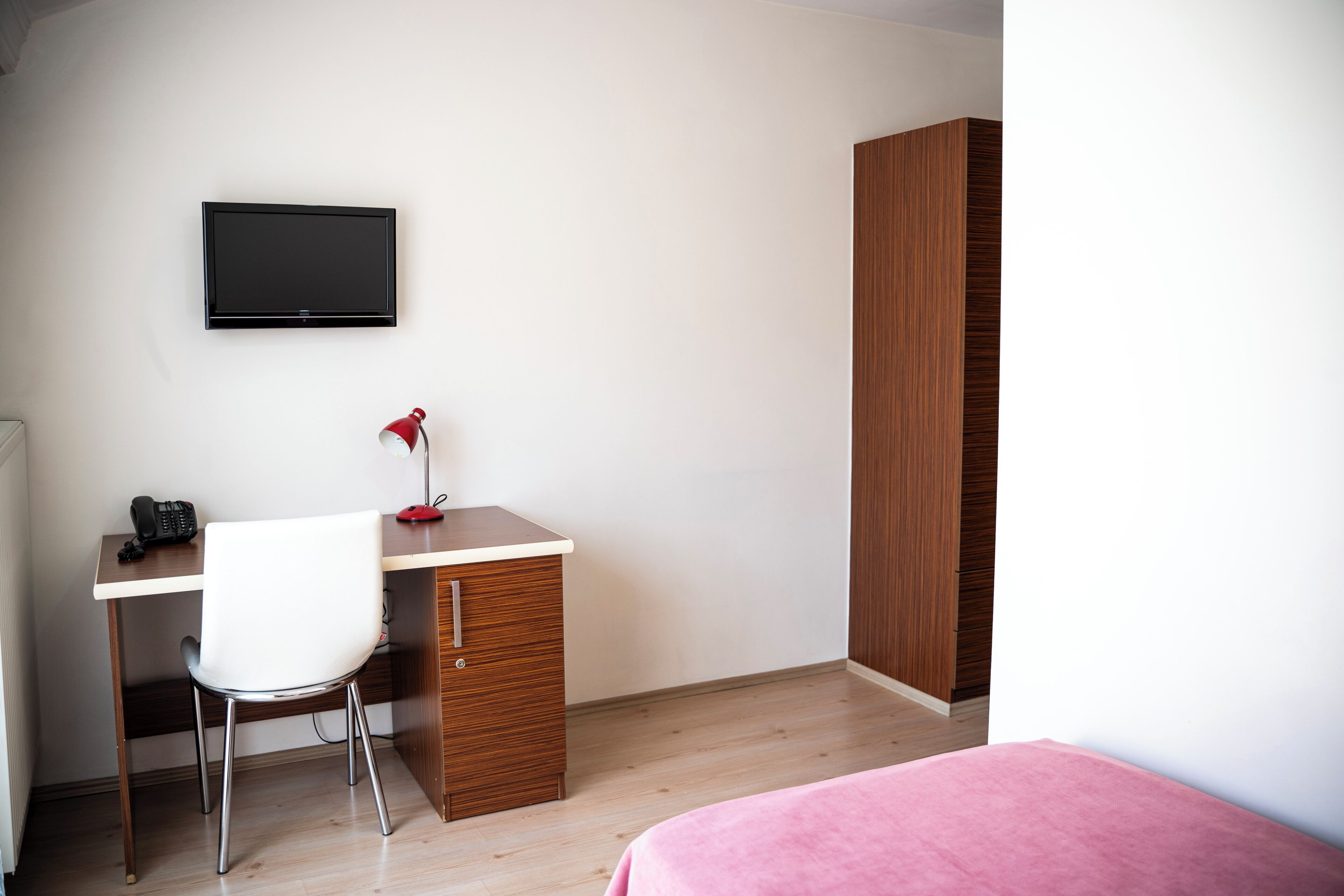 Un dormitorio con cama, escritorio con silla, televisor y armario.