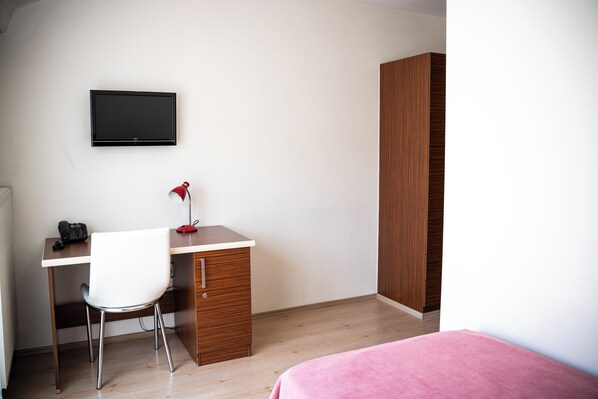 A bedroom with a bed, a desk with a chair, a TV, and a wardrobe. - Şirin Rezidence (Denizli)