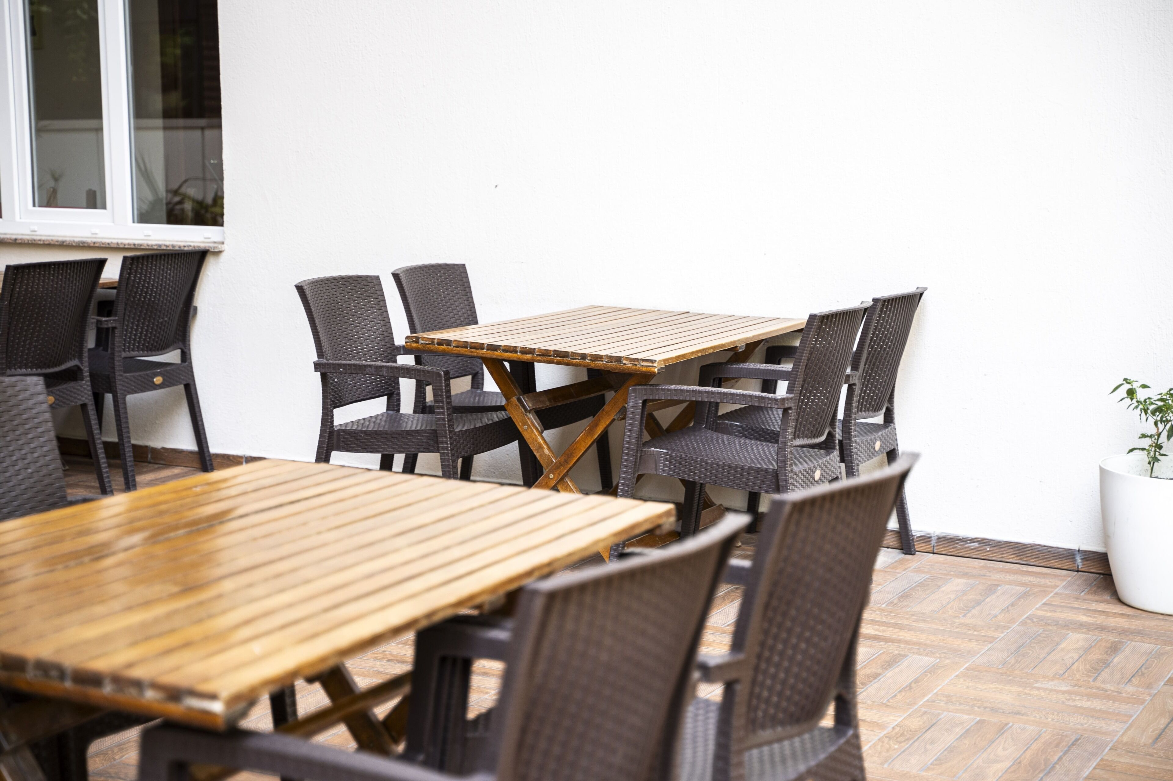 An outdoor patio area with a wooden table and wicker chairs.