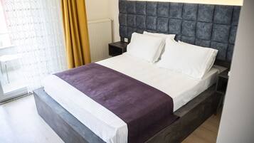A modern bedroom with a large bed, a headboard, and a nightstand.