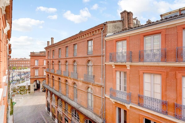 A multi-story building with a courtyard, featuring balconies with wrought iron railings and arched windows.