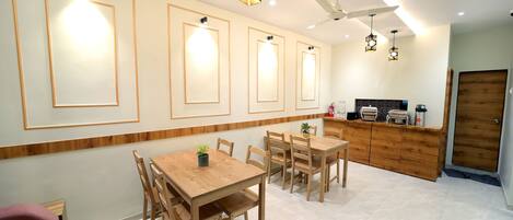 Una cocina moderna con armarios de madera, un comedor con mesa y sillas de madera, lámparas colgantes y un ventilador de techo.