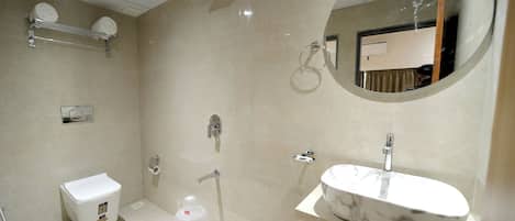 Un baño moderno con lavamanos de mármol, ducha e inodoro.