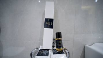 A bathroom with a white towel rack holding a white box and a bottle of shampoo.