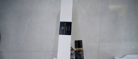 Une salle de bain avec un porte-serviettes blanc sur lequel est posée une boîte blanche et une bouteille de shampoing.