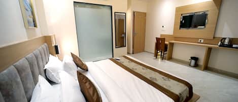 Une chambre d’hôtel avec un grand lit, un téléviseur fixé au mur et un petit bureau.