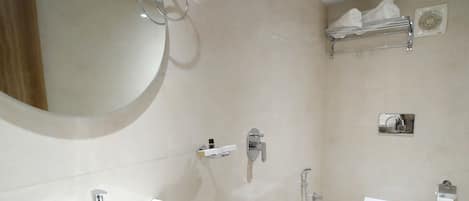 Un baño moderno con un espejo grande, un lavamanos blanco, ducha y un inodoro.