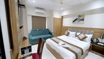 Una habitación de hotel con cama, escritorio, silla, sofá y ventilador de techo.
