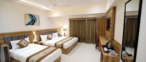 Habitación de hotel con dos camas, un escritorio, un espejo y un ventilador de techo.
