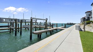 A waterfront promenade with wooden docks and benches, a clear sky, and buildings in the background. - Special Savings January 2024 31 days minimum! (Naples)