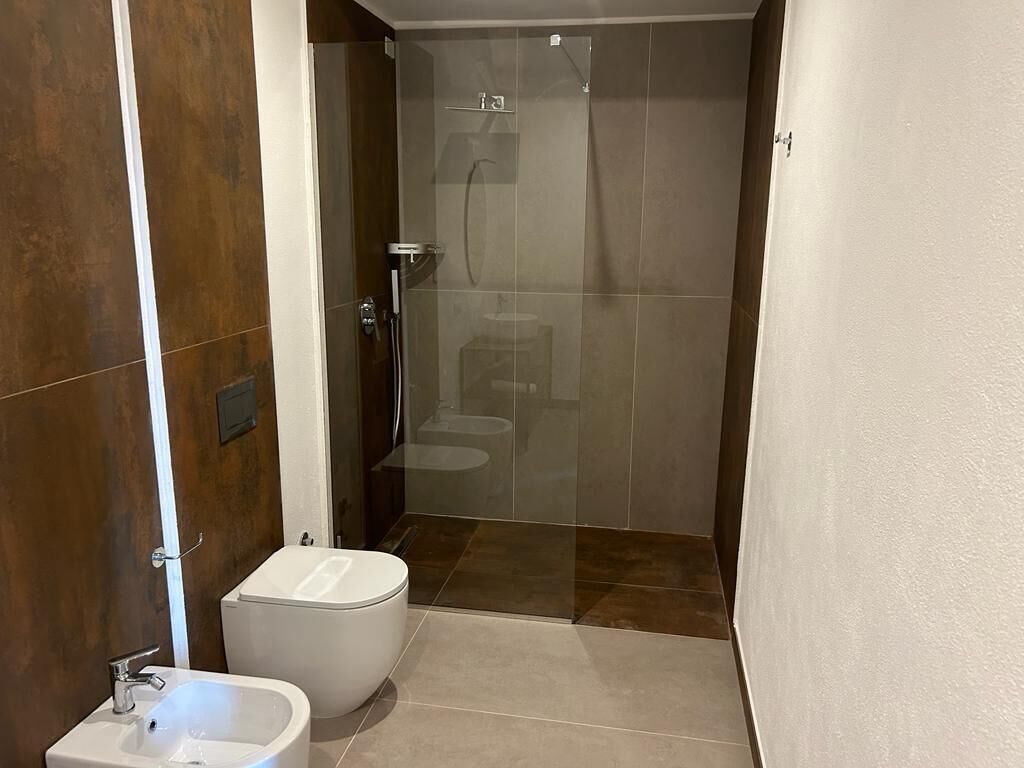 A modern bathroom with a shower, toilet, and bidet.