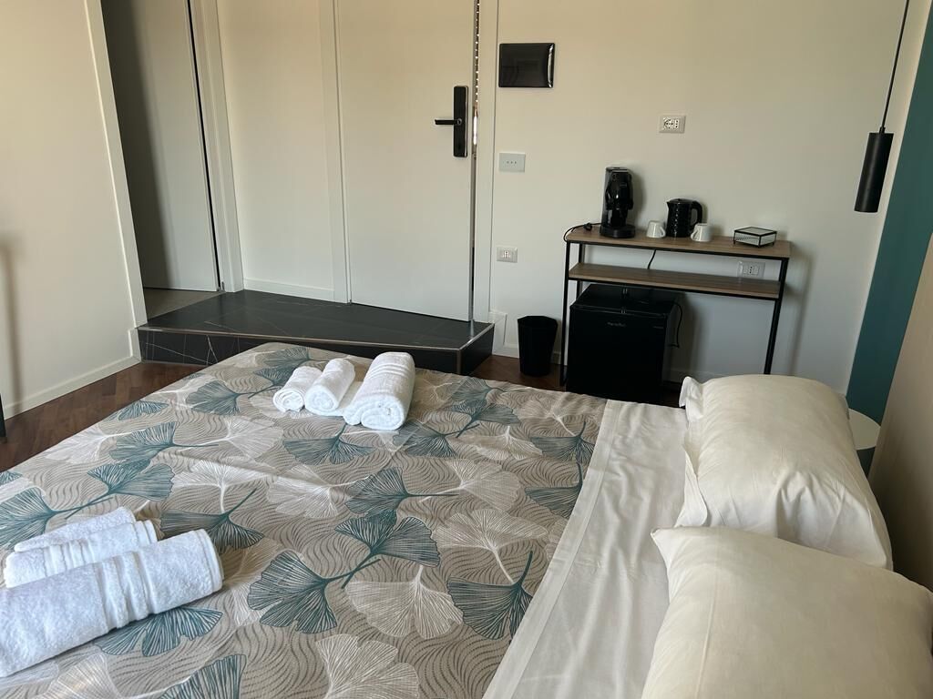 A hotel room with a bed, a desk, and a coffee machine.
