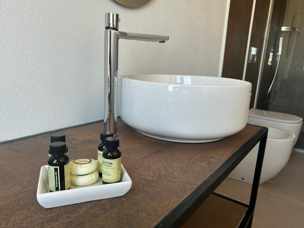 Een badkamer met een wit wastafel, een moderne kraan en een klein dienblad met toiletartikelen.
