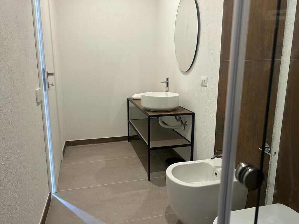 Un baño con lavamanos blanco, un espejo y un bidé.