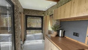 A modern kitchen with wooden cabinetry, a stainless steel sink, and a built-in stove. - Duas Quintas Areal - Estudio com Vista Jardim (Nespereira GMR)