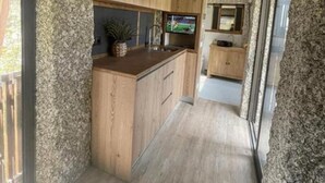 A modern kitchen with wooden cabinets, a granite countertop, and a built-in oven. - Duas Quintas Areal - Estudio com Vista Jardim (Nespereira GMR)
