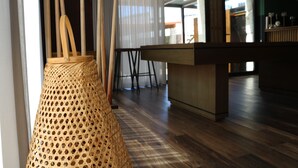 A room with a wooden floor, a woven basket hanging from the ceiling, and a bar area with stools. - Duas Quintas Areal - Estudio com Vista Jardim (Nespereira GMR)