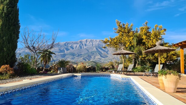 A swimming pool with a mountain backdrop, surrounded by various plants and trees. - Casa El Mirador Offers Spectacular Views, Comfort, and a Heated Pool (arenas)