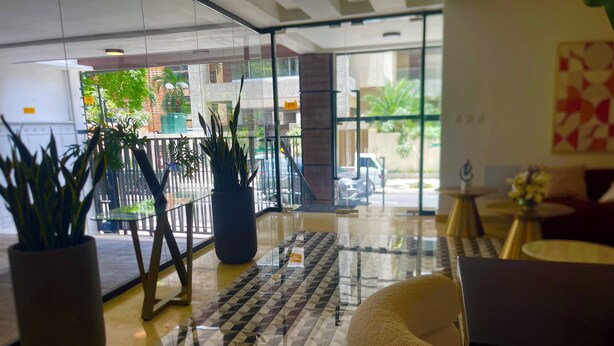 A lobby with a checkered floor, potted plants, and a seating area. - Luxury in Naco 2BR: Pools, gym, views, bars and more (Santo Domingo)