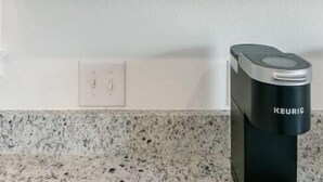 A kitchen with a coffee maker, jars, and a framed picture on the wall. - Chic studio near ACU (Abilene)
