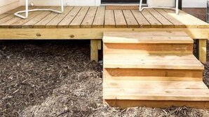 A wooden deck with two white chairs and a black door. - Chic studio near ACU (Abilene)