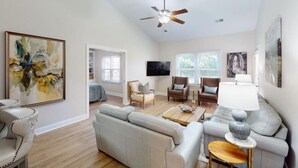 A spacious living room with a large sofa, two armchairs, a coffee table, and a ceiling fan.