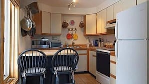 A compact kitchen with two black chairs, a microwave, a stove, and a refrigerator. - 4 Season Spyglass Townhouse on Haystack Golf Course
Ski/Board/Golf/Hike/Relax (Wilmington)