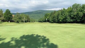 A golf course with a flagstick in the center, surrounded by trees and a mountain in the background. - 4 Season Spyglass Townhouse on Haystack Golf Course
Ski/Board/Golf/Hike/Relax (Wilmington)