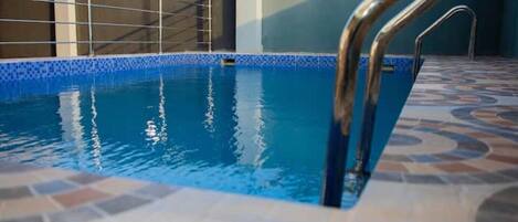 Swimmers can enjoy a refreshing dip in the pool surrounded by a geometric tile floor.